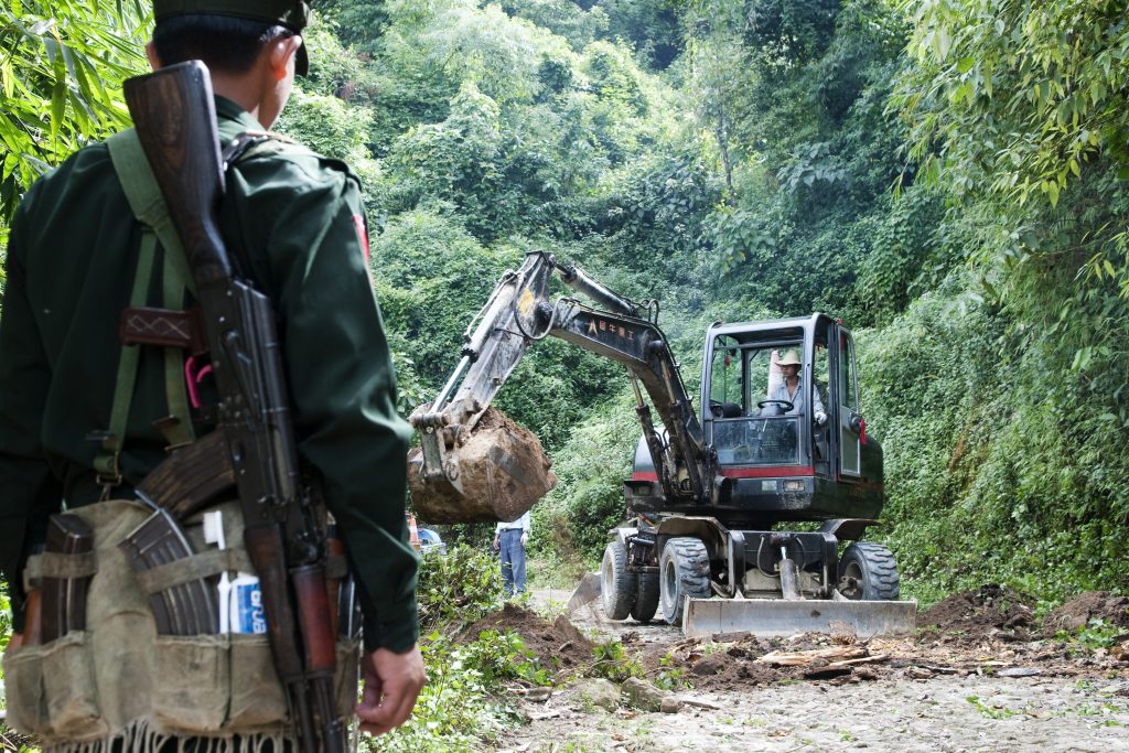 Un soldado del Ejército de Independencia Kachin (KIA) observa una excavadora que despeja un camino en la selva de Birmania (Myanmar).