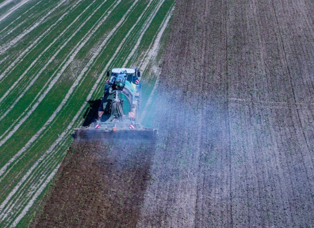 Un tractor arrastra un remolque de fertilizantes por un campo de Mecklemburgo-Pomerania Occidental, en Alemania (imagen desde un  dron).