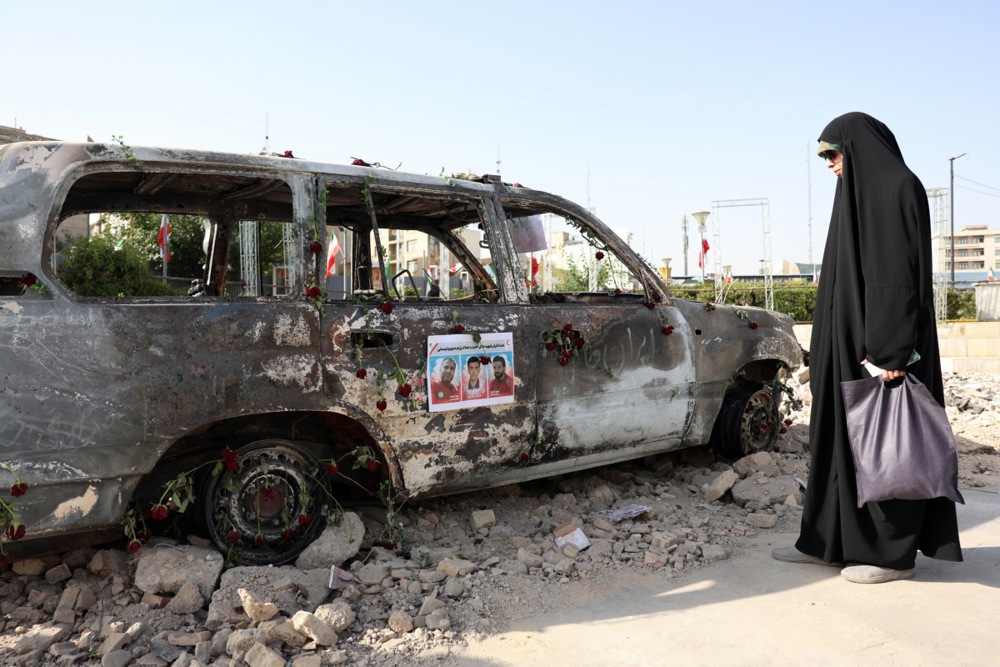 Una mujer iraní  junto a una ambulancia de la Sociedad de la Media Luna Roja Iraní (IRCS) que fue destruida en un ataque israelí, en Teherán, Irán, 23 de junio de 2025.