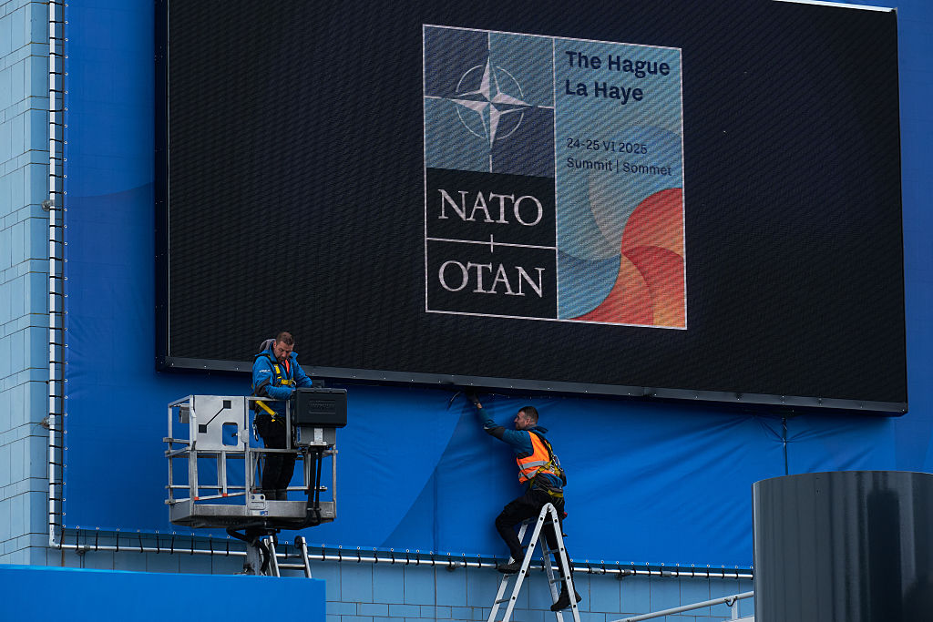 Un trabajador coloca una pancarta alrededor de una pantalla con el logotipo de la OTAN en un edificio que se prepara para albergar la Cumbre de la OTAN el 10 de junio de 2025 en La Haya, Países Bajos.