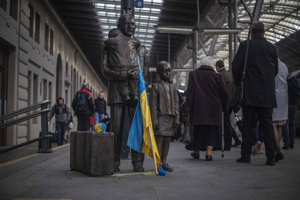 La estatua de Sir Nicholas Winton, que salvó a 669 checoslovacos, principalmente niños judíos, de ser deportados a campos de concentración antes de la Segunda Guerra Mundial,  decorada con la bandera ucraniana, en la estación de tren central de Praga, como símbolo para recibir a los refugiados ucranianos.