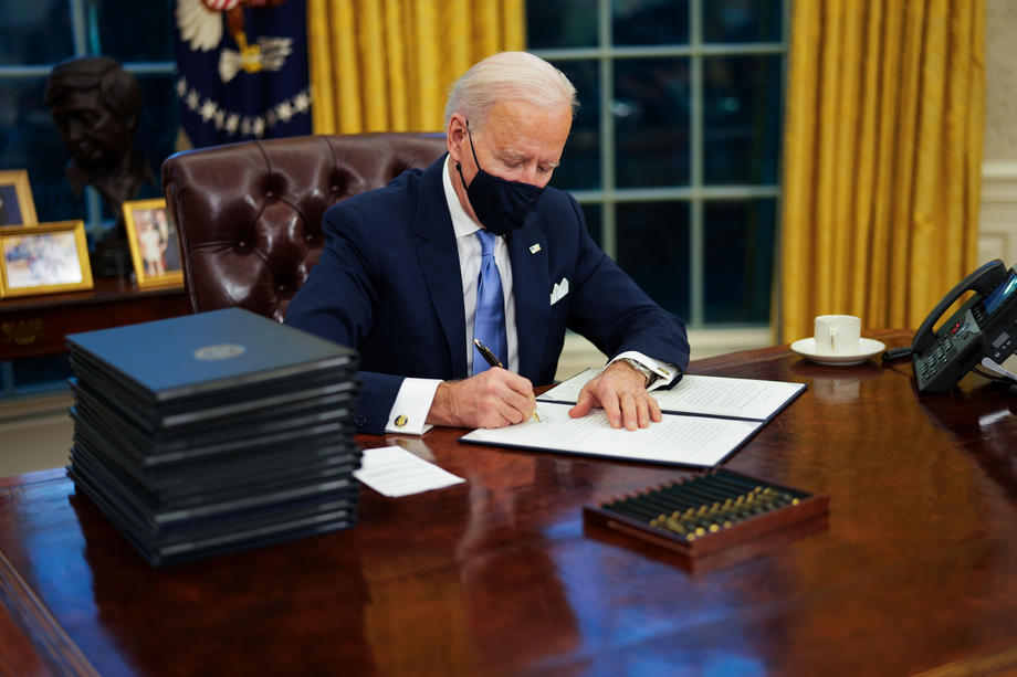 US President Joe Biden signs executive orders during his first minutes in the Oval Office