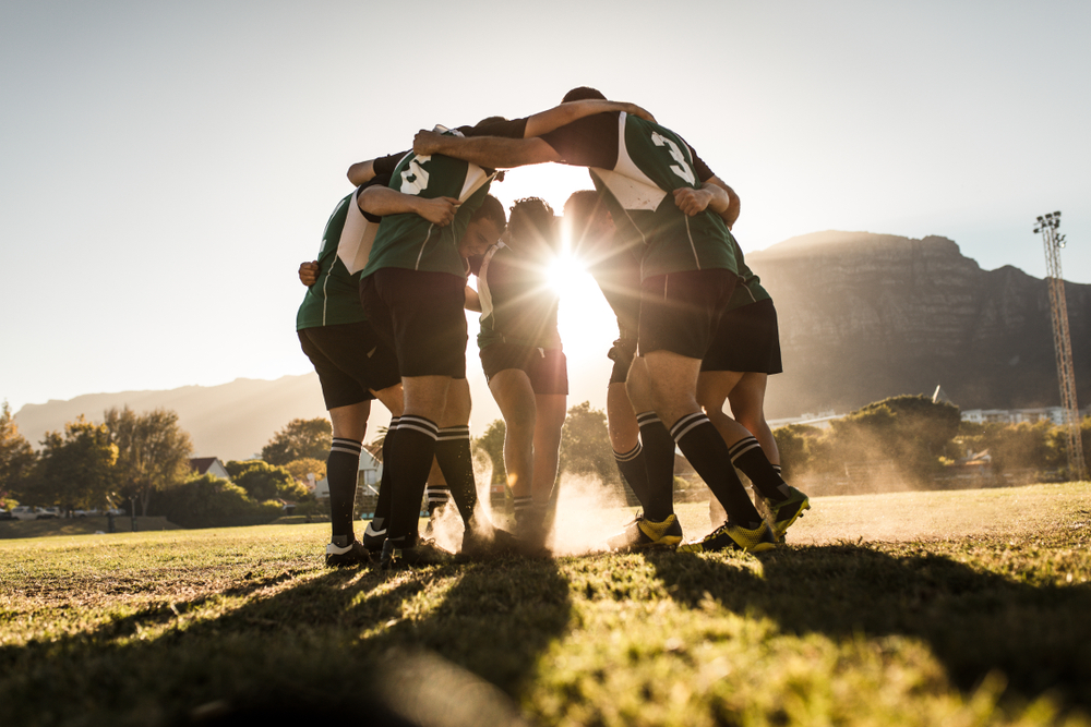 Rugby,Team,Standing,In,A,Huddle,And,Rubbing,Their,Feet