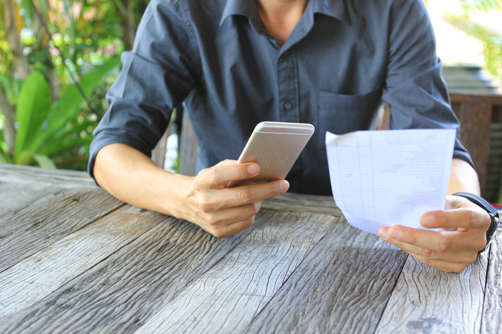 Businessman,Holding,Mobile,Phone,With,Bill,Paper,In,Restaurant