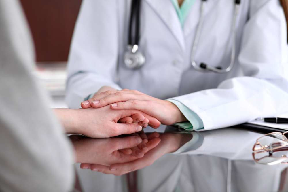 Friendly,Female,Doctor,Hands,Holding,Patient,Hand,Sitting,At,The