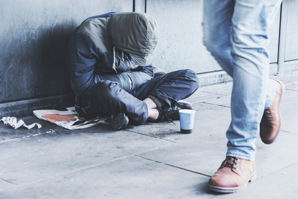 Homeless,Man,Sitting,On,The,Street,In,The,Shadow,Of