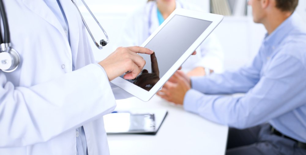 Doctor,Using,Tablet,Computer,,Close-up,Of,Hands,At,Touch,Pad