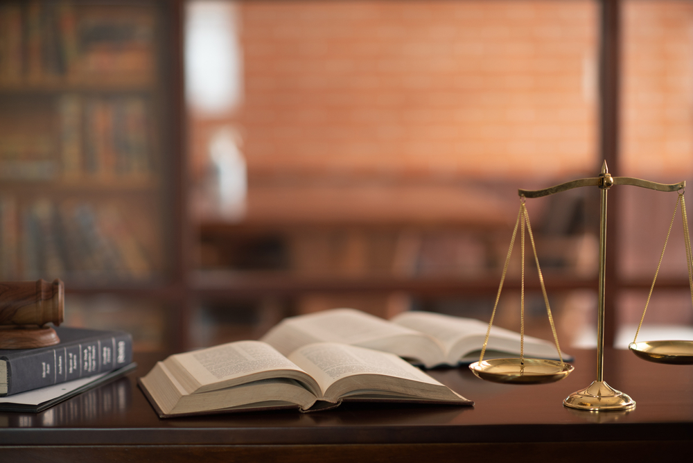 Law,Books,And,Scales,Of,Justice,On,Desk,In,Library