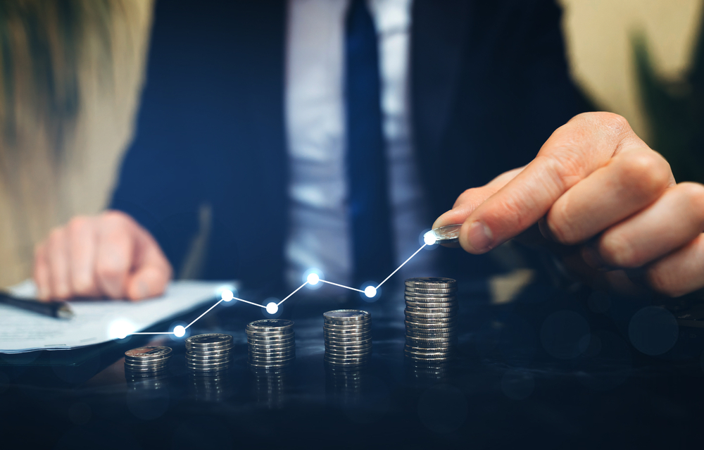 Businessman,Stacking,Coins,With,A,Graph,Of,Profit.,Business,Successful