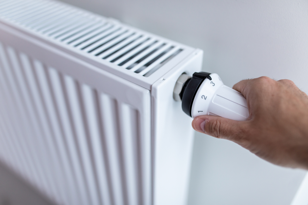Woman,Holding,Temperature,Knob,Of,Heating,Radiator