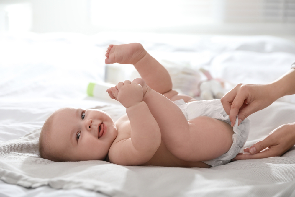 Mother,Changing,Her,Baby&rsquo;s,Diaper,On,Bed