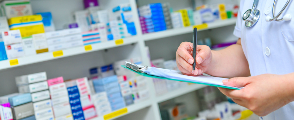 Doctor,Writing,Prescription,With,Many,Medicine,On,Shelves,Background