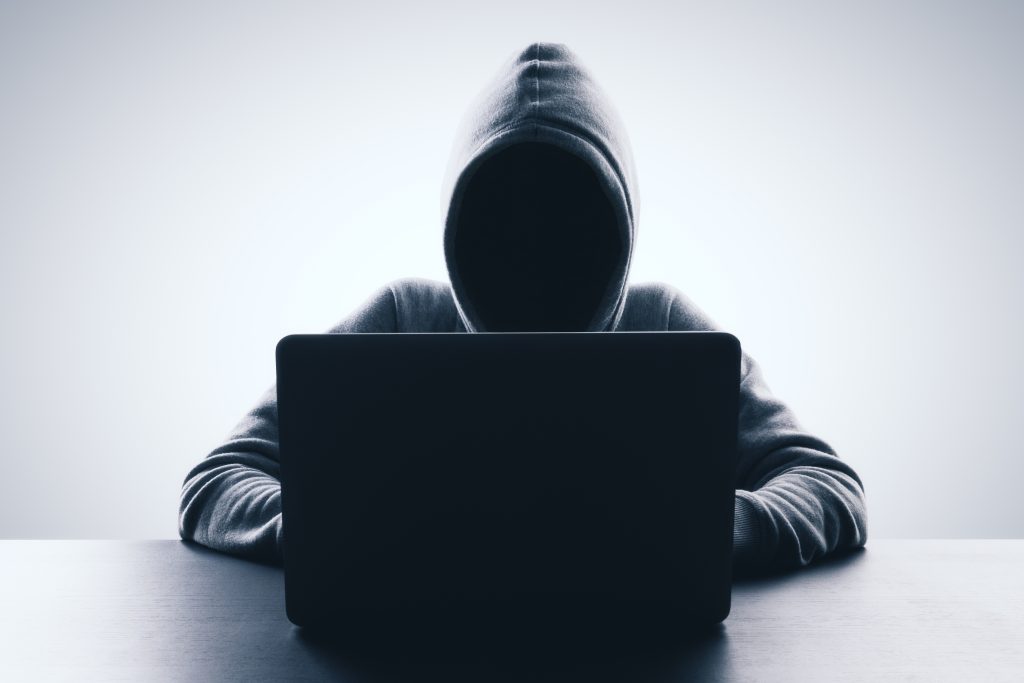 Man,With,Hood,Using,Laptop,On,Gray,Background.,Hacker,And
