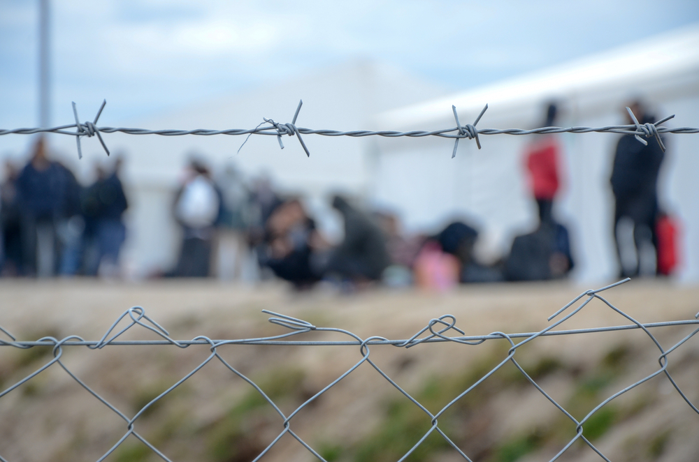 Barbed,Wire,In,Refugee,Camp.,Migrants,Behind,Chain,Link,Fence