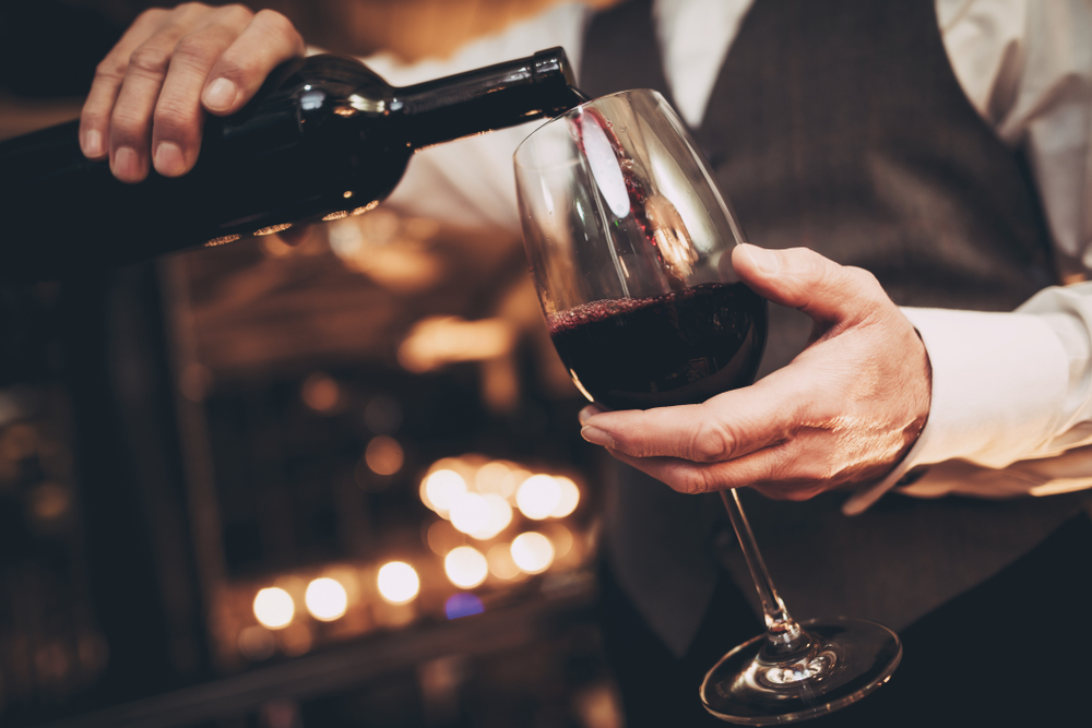 Close,Up.,Elegant,Waiter,Pours,Red,Wine,From,Bottle,Into