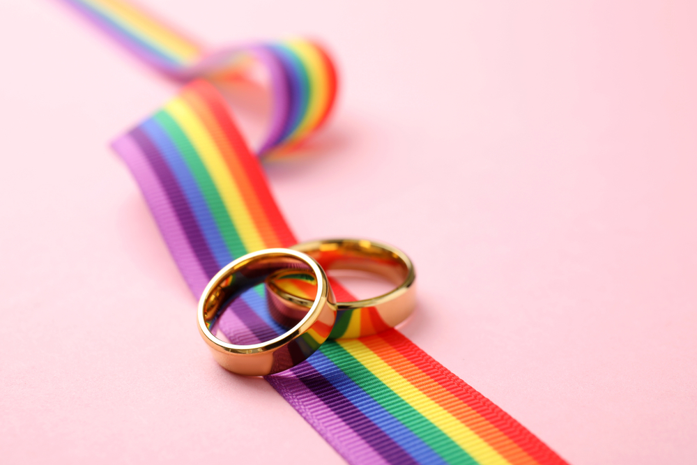 Wedding,Rings,And,Rainbow,Ribbon,On,Color,Background,,Space,For