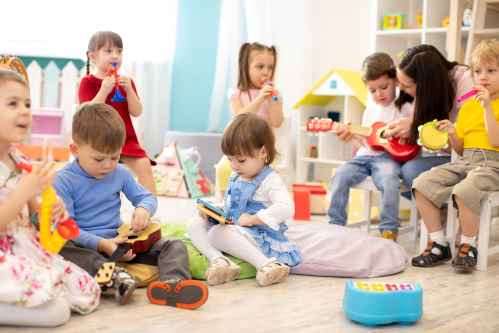 Kindergarten,Teacher,With,Children,On,Music,Lesson,In,Day,Care.