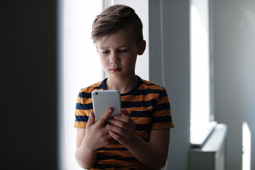 Sad,Little,Child,With,Smartphone,Indoors.,Danger,Of,Internet