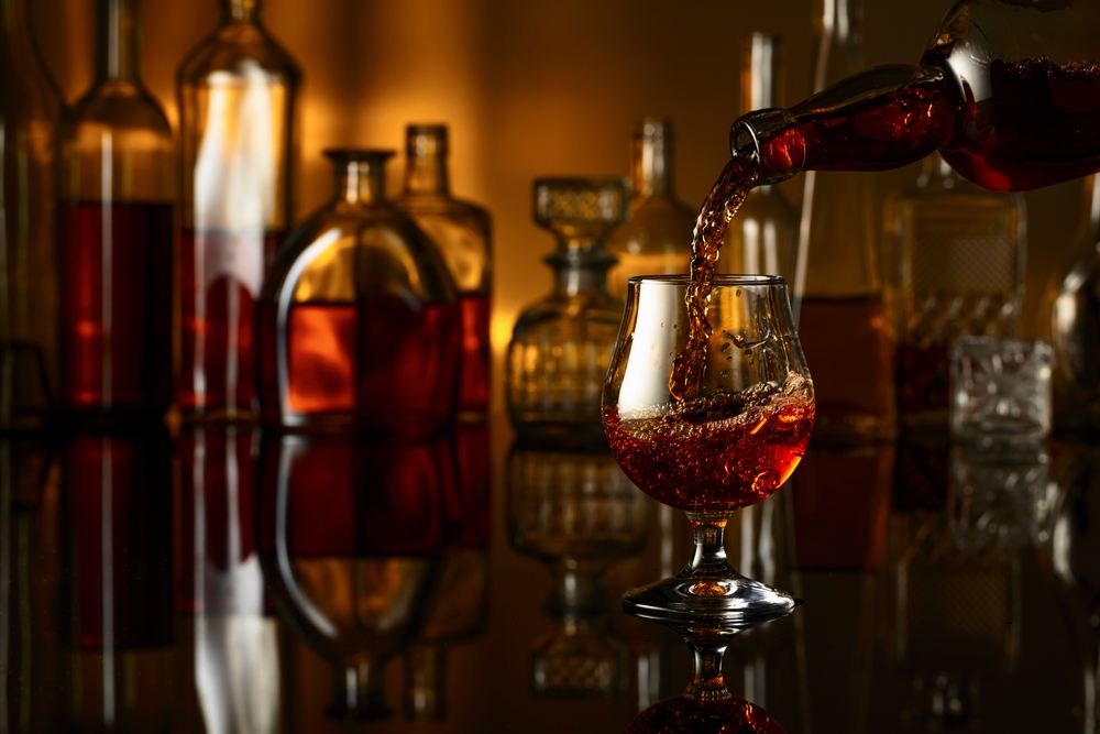 Brandy,Is,Poured,From,A,Bottle,Into,A,Glass.,Snifter