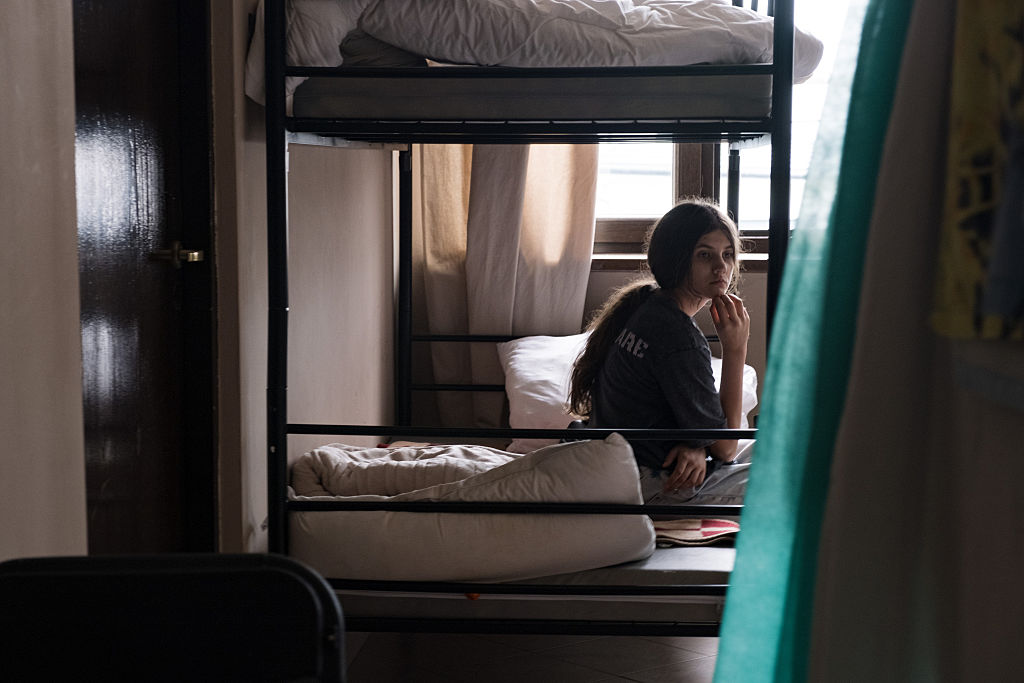 A refugee is seen sitting on the assigned bed in the shelter