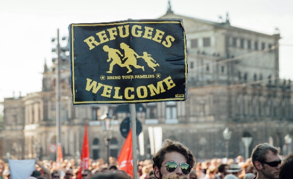 Teilnehmer einer Demonstration stehen mit einem Schild mit der Aufschrift „Refugees welcome“ in der Dresdner Innenstadt.