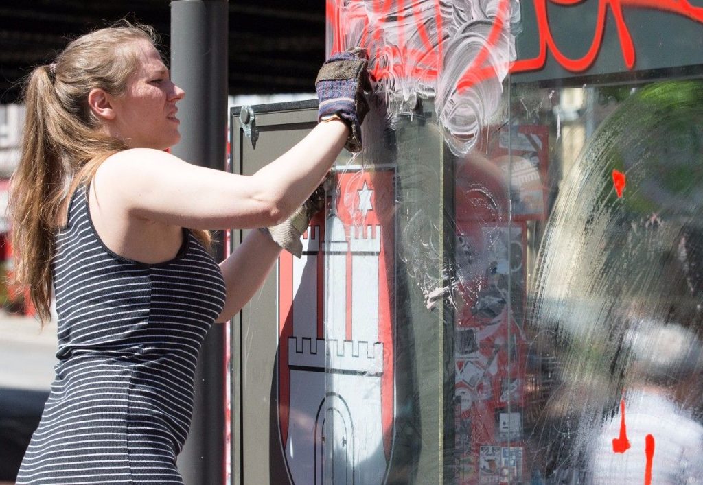 epa06077768 A resident of the ‚Schanzenviertel‘ district cleans the remains of a bus stop shattered and smeared in clashes during the recent G20 summit in Hamburg, northern Germany, 09 July 2017. The G20 Summit (or G-20 or Group of Twenty), an international forum for governments from 20 major economies that took place in Hamburg on 07 and 08 July, sparked violent protest actions across the city, with dozens of injured people and heavy material damages.  EPA/ALEXANDER BECHER
