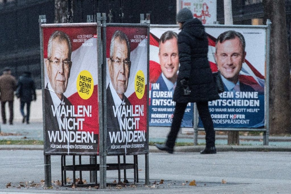 epa05653936 A woman passes presidential election campaign posters of right-wing Austrian Freedom Party (FPOe) presidential candidate Norbert Hofer (L), reading ‚In eurem Sinne entscheiden – So wahr mir Gott helfe‘ (To decide with your best interest in mind – So help me God), and Alexander Van der Bellen (R), who is supported by the Greens, reading ‚Waehlen nicht wundern‘ (Vote! Don’t be surprised), at the Vienna Ring Road in Vienna, Austria, 30 November 2016. The Austrian Presidential election runoff will take place on 04 December 2016.  EPA/CHRISTIAN BRUNA