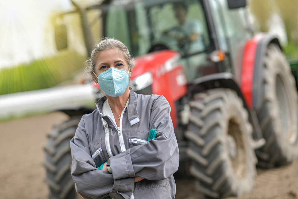 Female,Farmer,Standing,In,Front,Of,A,Tractor,And,Wearing