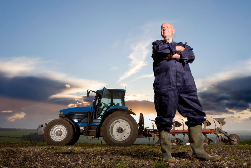 Old-aged,Farmer,Standing,With,Arms,Crossed,In,His,Field,Wearing