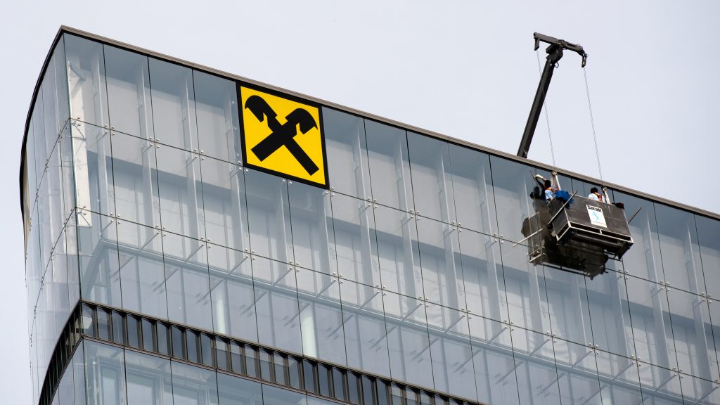 epa05243517 The logo of Raiffeisen Bank International (RBI) with window cleaners working on the facade at one of its buildings in Vienna, Austria, 03 April 2016.  EPA/CHRISTIAN BRUNA