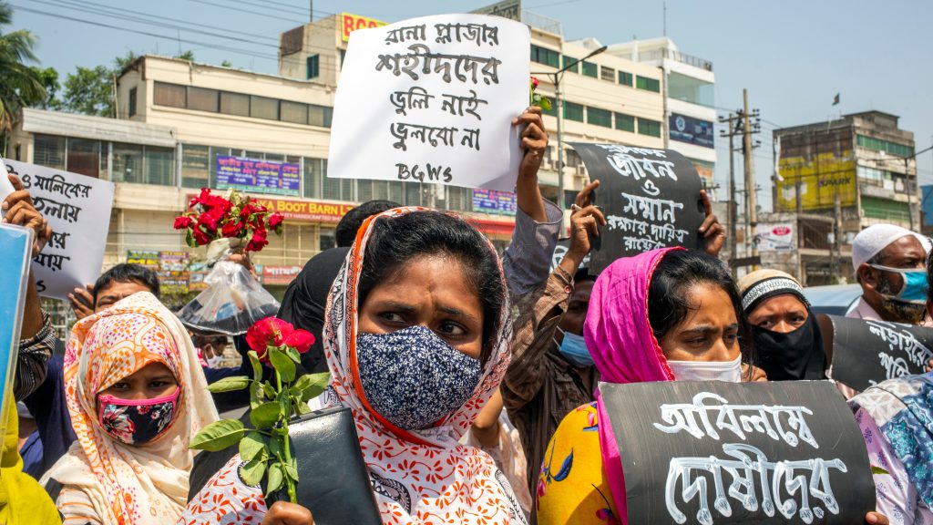 epa09156189 Members of a labor rights organization hold placards and flowers to pay tribute at the site where the Rana Plaza building once stood in the outskirt of Dhaka, Bangladesh, 24 April 2021, the eighth anniversary of the disaster. Several garment manufacturer organizations and family members attended the anniversary at Rana Plaza building site where at least 1,134 people died and some 2,500 were injured after the garment factory building collapsed on 24 April 2013.  EPA-EFE/MONIRUL ALAM