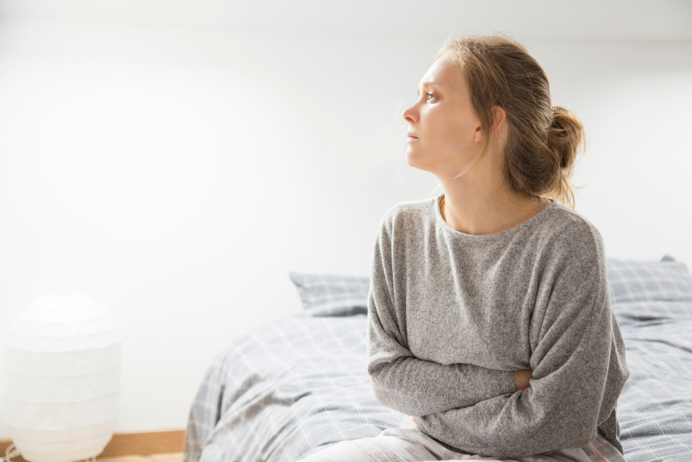 Sad,Stressed,Girl,Suffering,From,Stomach,Pain.,Young,Woman,Sitting