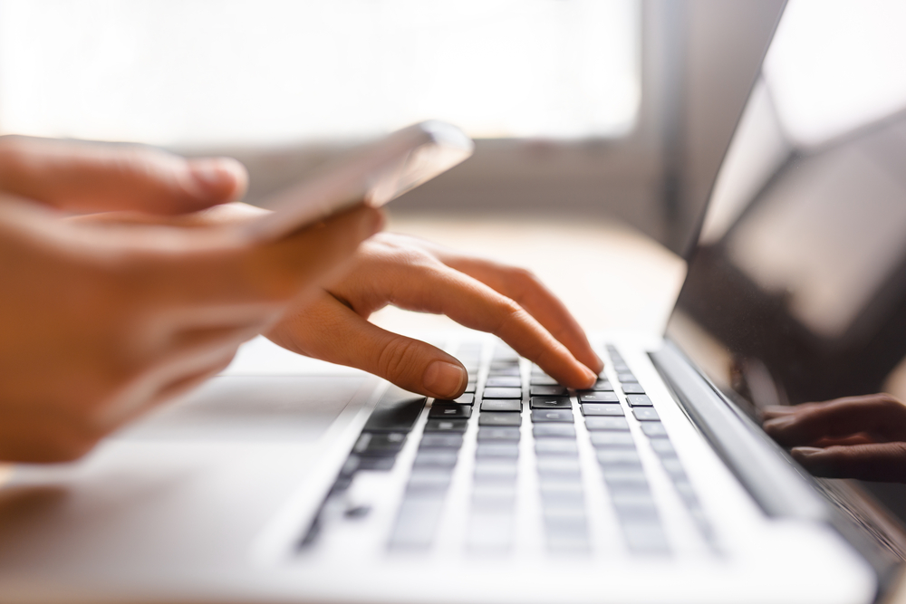 Hands,Using,Laptop,And,Phone,For,Online,Shopping,,Close,Up