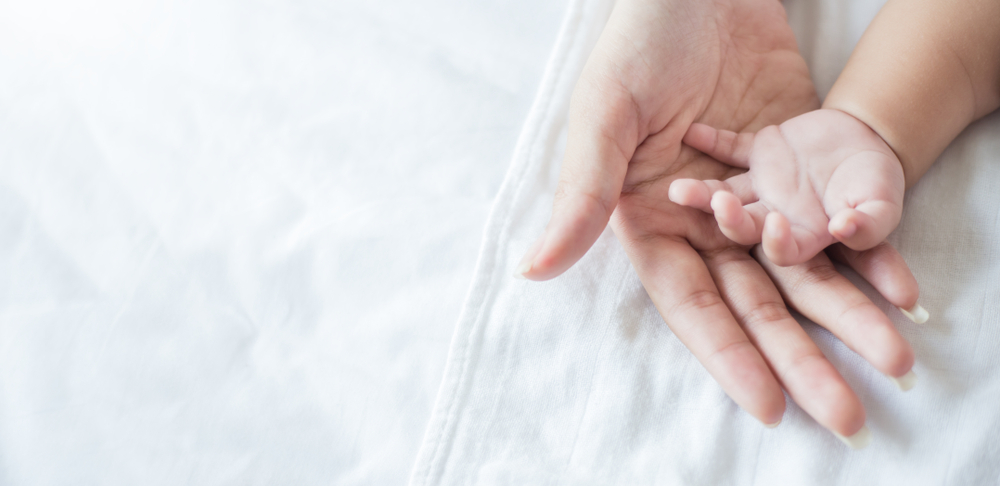 Asian,Parent,Hands,Holding,Newborn,Baby,Fingers,,Close,Up,Mother’s