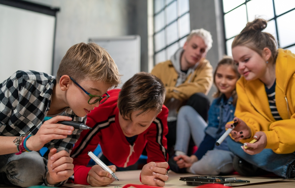 Group,Of,Happy,Kids,With,Their,Teacher,Working,On,Project