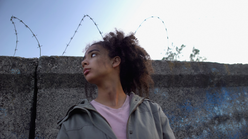 Biracial,Teenage,Girl,Standing,Behind,Wire,Fence,,Dreaming,To,Escape