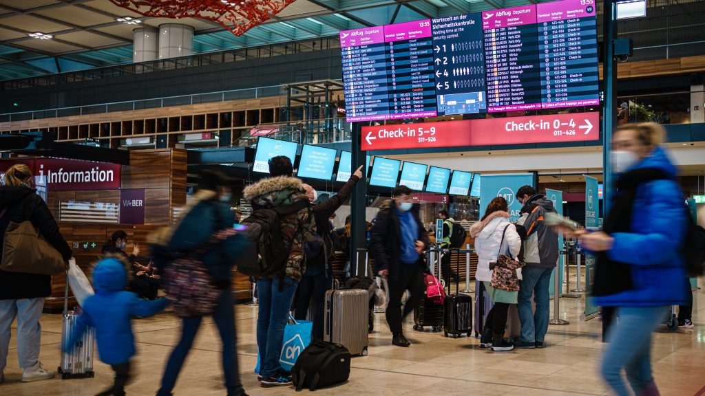 epa09658023 Passengers move in front of an electronic display at Berlin-Brandenburg airport BER in Schoenefeld near Berlin, Germany, 27 December 2021. Despite thousands of canceled flights due to sick notes of flight crews in connection with rising numbers of Omicron variant coronavirus infections in the US, the situation at the German capital’s Berlin-Brandenburg airport BER showed only few canceled flights during the the day of 27 December 2021.  EPA-EFE/CLEMENS BILAN