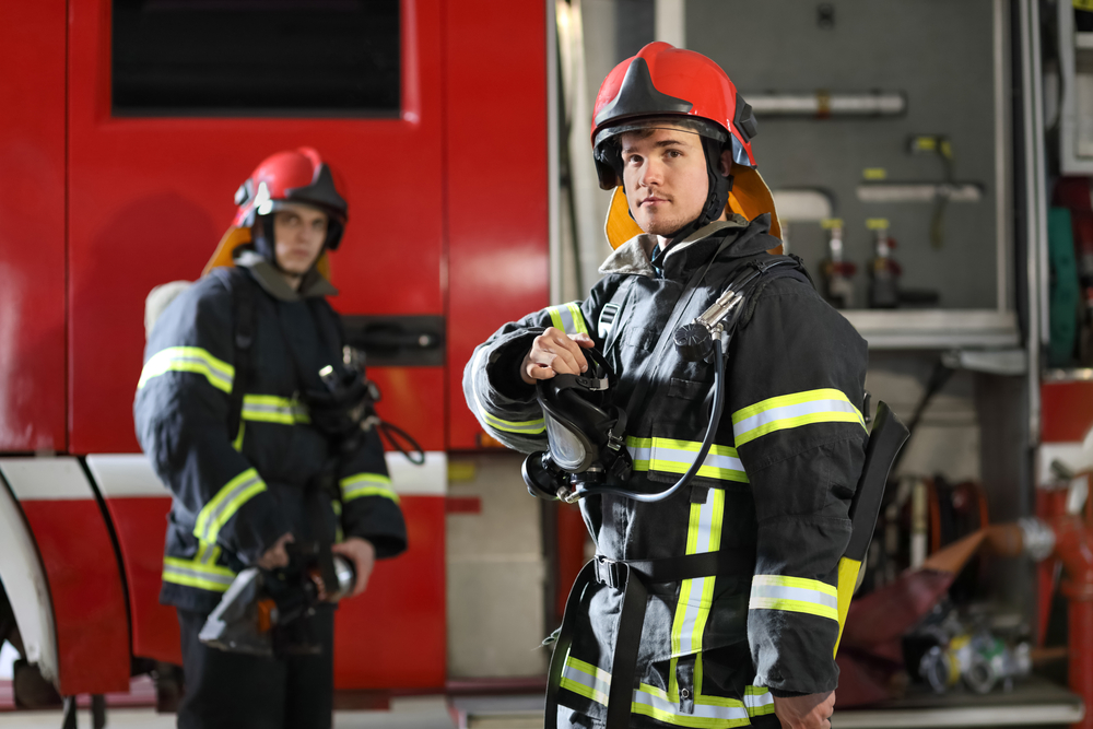 Two,Firefighters,In,Protective,Clothing,,Helmets,And,Mask,Against,Fire