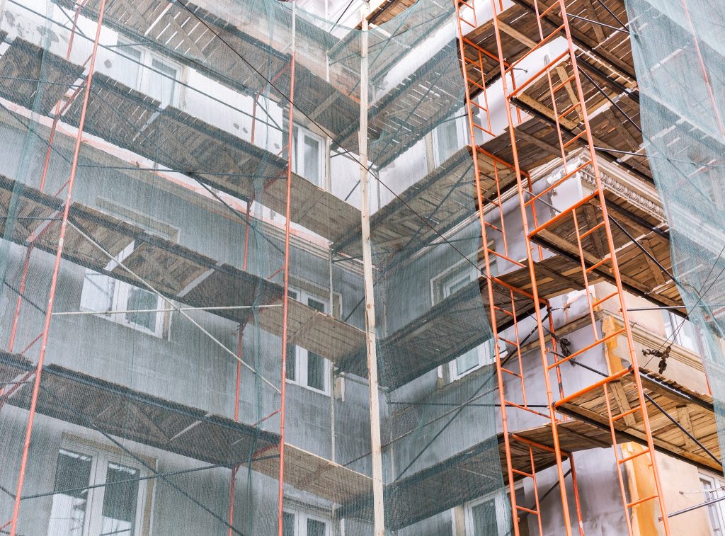 Apartment,Building,Exterior,Under,Renovation,With,Scaffolding,And,Green,Netting