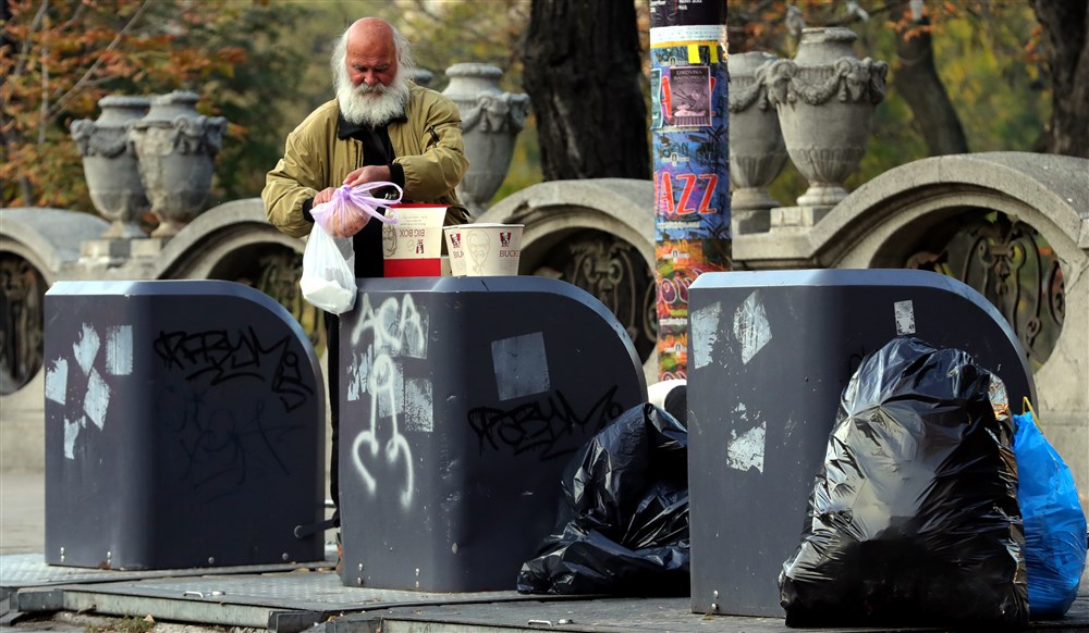 Old man collects food from a garbage cans