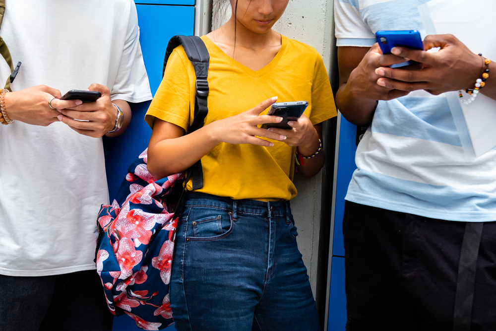 Close-up,Of,Teen,High,School,Students,Using,Mobile,Phone,In