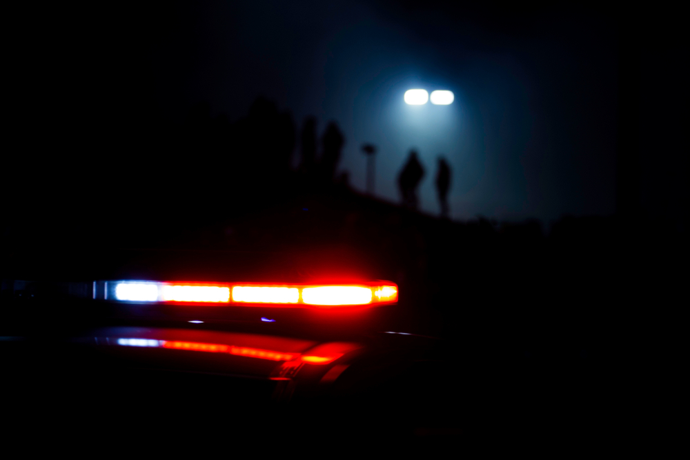 Police,Lights,Flash,As,People,Are,Silhouetted,In,The,Background