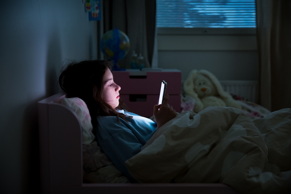 A,Child,Using,Smart,Phone,Lying,In,Bed,Late,At