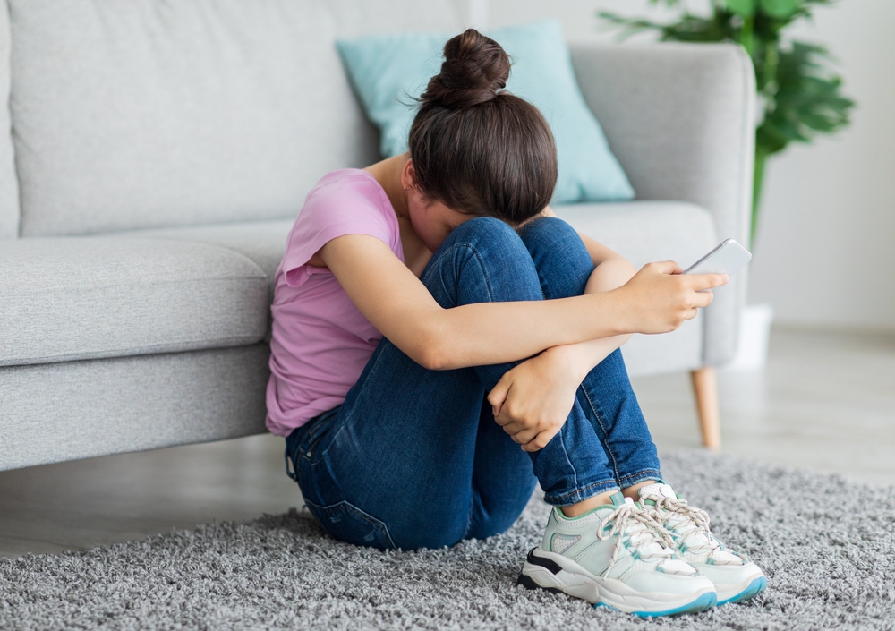 Depressed,Indian,Teen,Girl,With,Cellphone,Crying,On,Floor,At