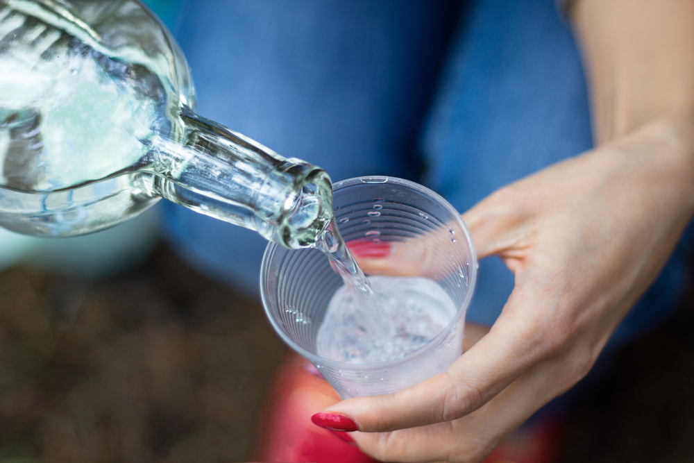 Girl,Pour,Beverage,From,Bottle,Into,Glass,In,Outdoor