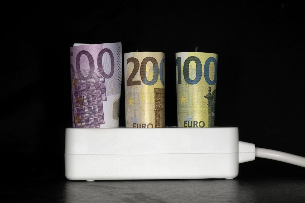 Symbol photo for electricity costs, socket with 3 banknotes, 500 €, 200€ and a 100€ banknote, studio photography with black background