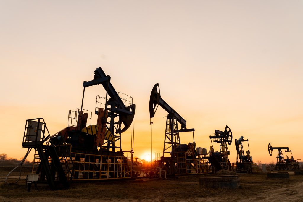The silhouette of five oil pumps on a beautiful sunset sky with sun setting in between them.Siberia. Oil and gas production