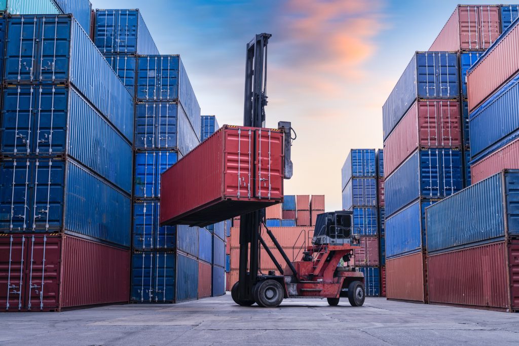 Industrial Container yard for Logistic Import Export business, Forklift truck handling cargo shipping container box in logistic shipping yard with cargo container stack, Crane lifting up container in yard