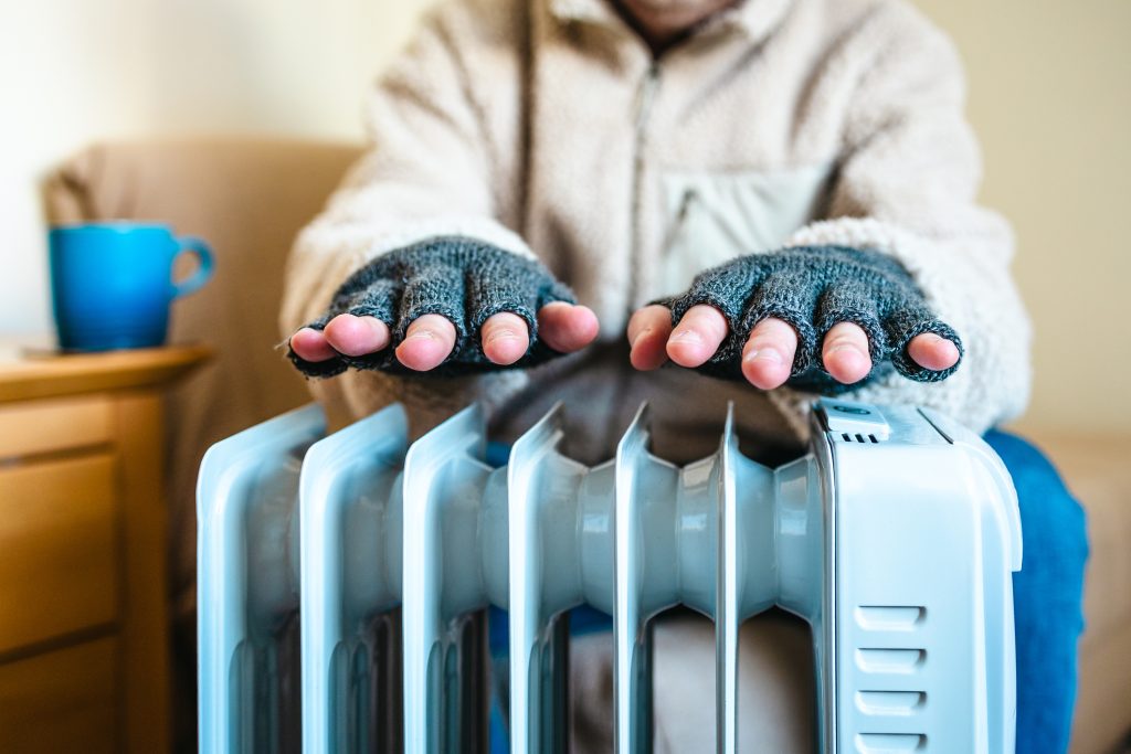 Warming cold hands over electric heater at home